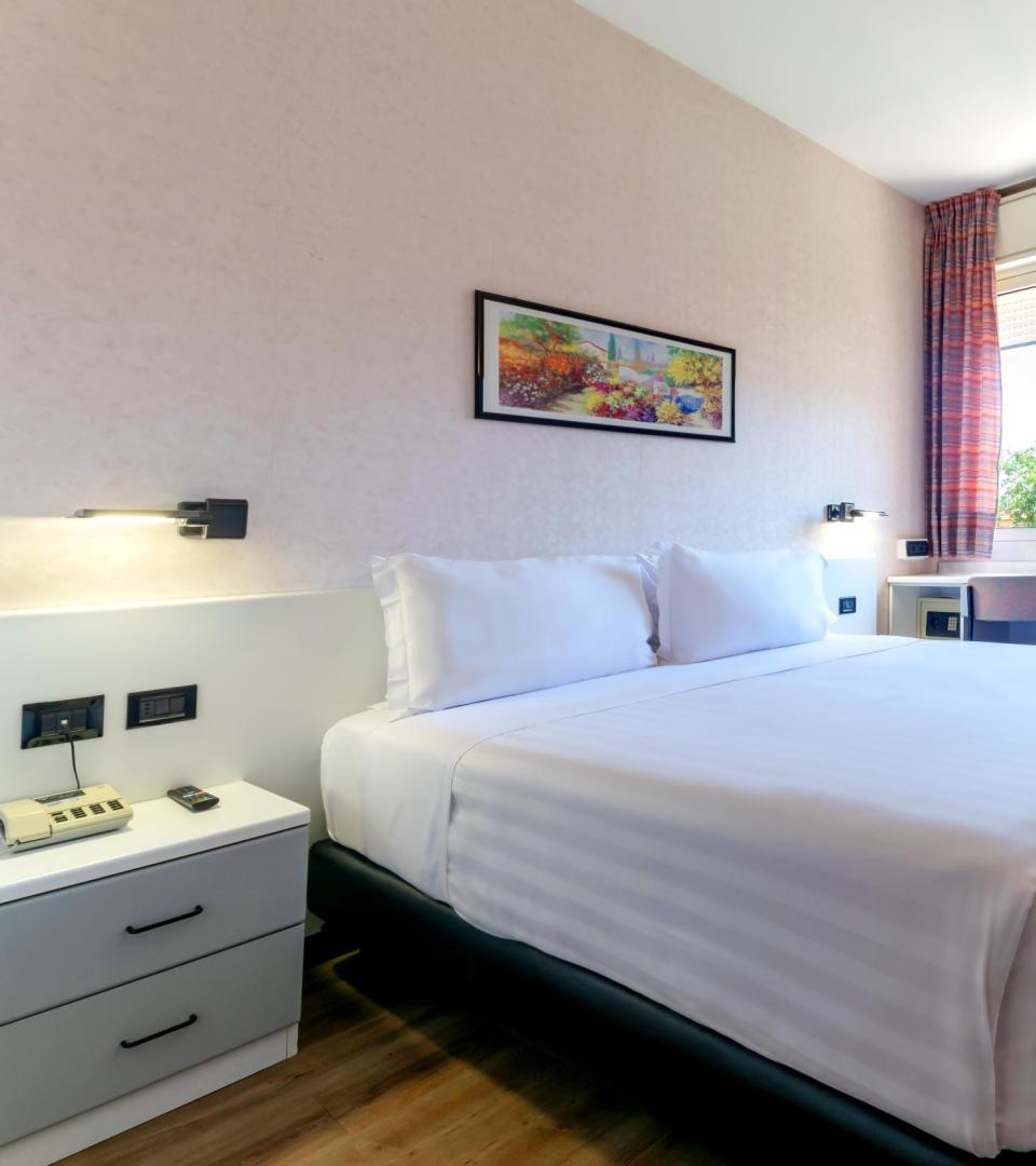 Camera moderna con letto matrimoniale e finestra luminosa.