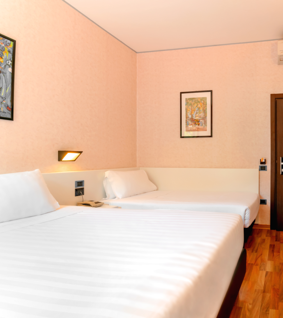 Camera d'albergo con due letti, aria condizionata e arredi moderni.